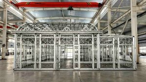 Wide front view of the large Victorian greenhouse framework with open double doors during the customer's factory inspection.